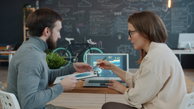 Two people sitting at a computer discussing graphs